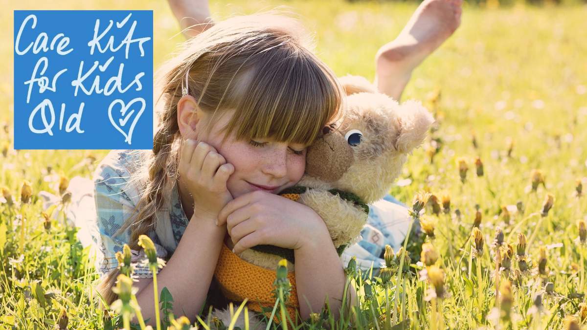 Young girl holding a teddy bear on the grass